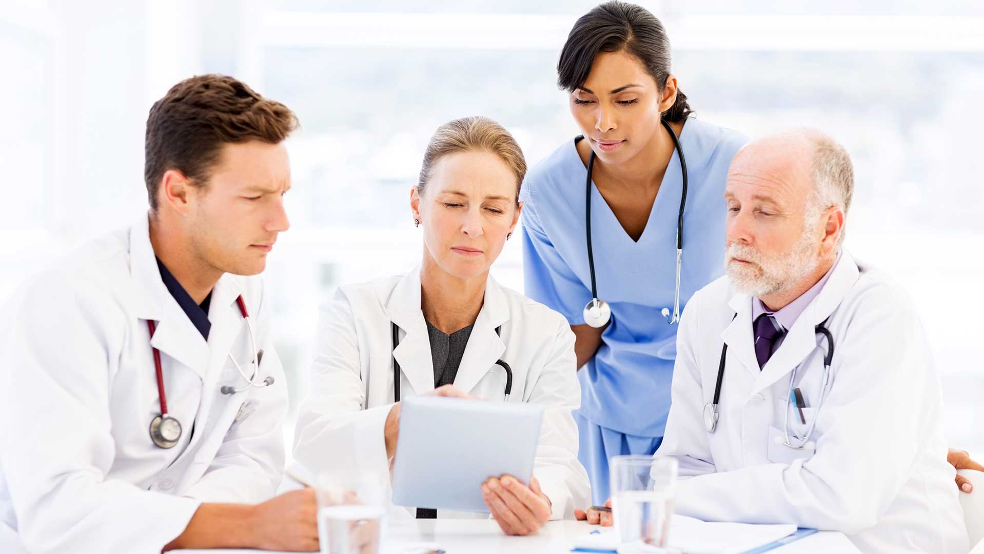  tre medici e un’infermiera che leggono alcuni dati su un tablet